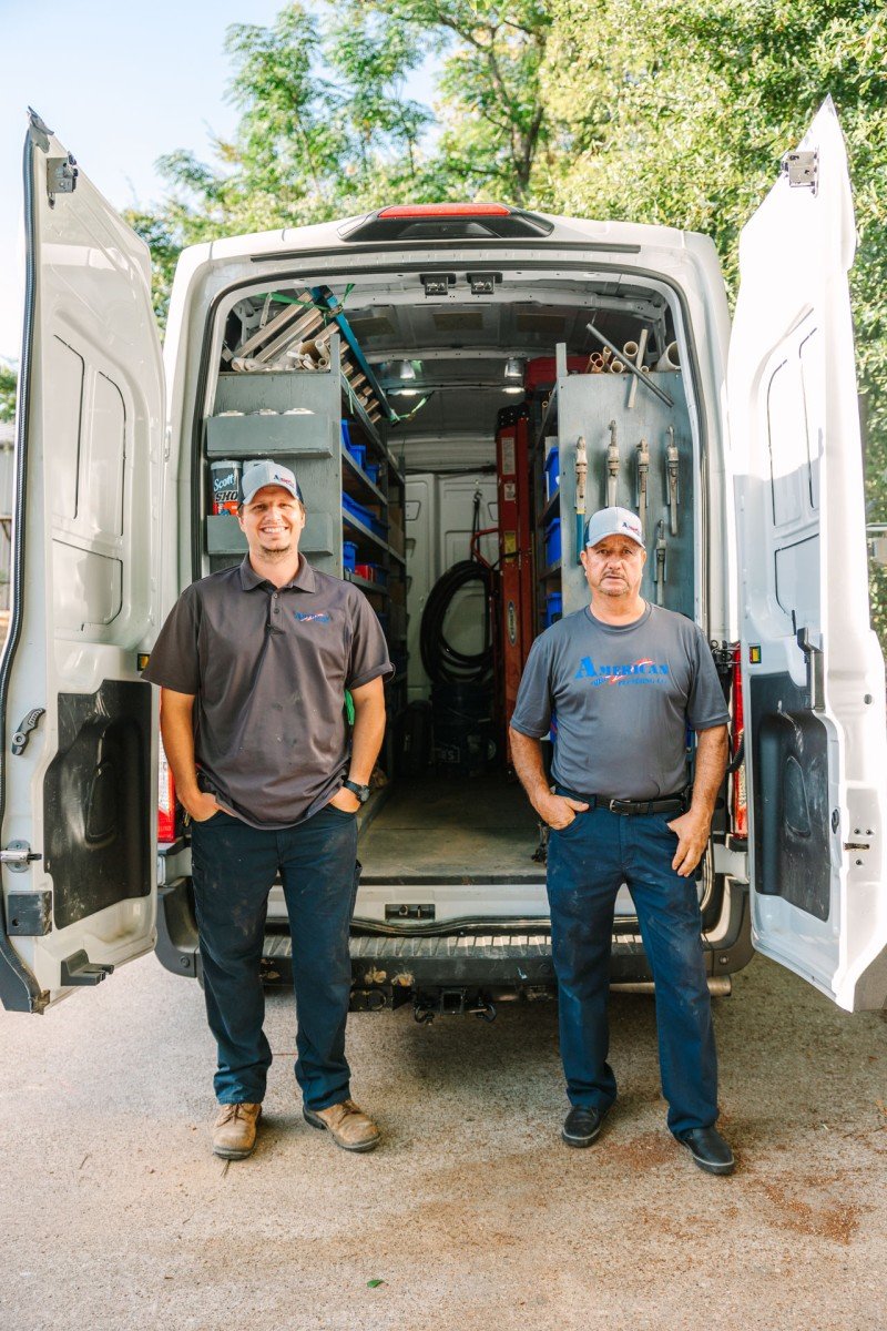 Professional plumbing service team standing by a stocked work van